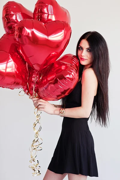 Hermosa joven morena con globos en forma de corazón. Día de San Valentín . — Foto de Stock