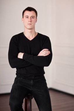 evde iskemlede siyah giysili adam.