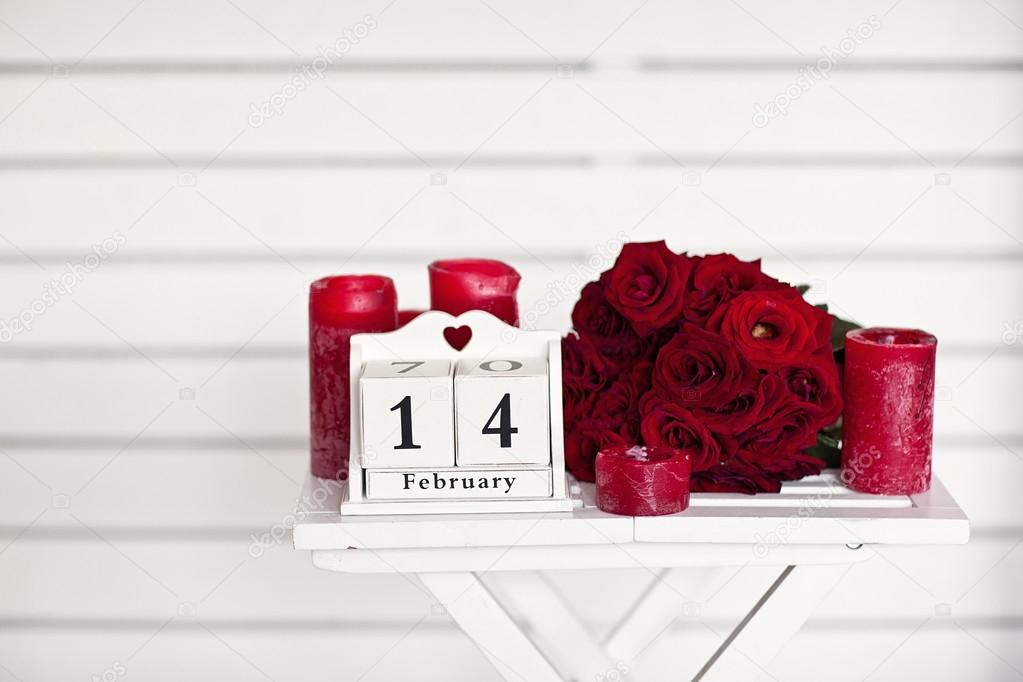 red roses lay on the table near calendar  with the date of Febru