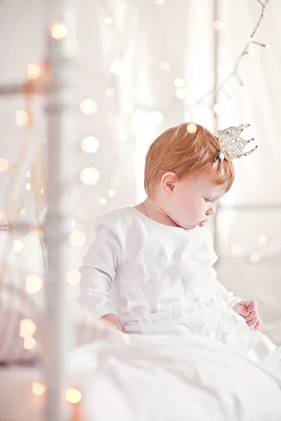 Vackra lcute rödhårig flicka sitter i vit säng. Princess säng. — Stockfoto