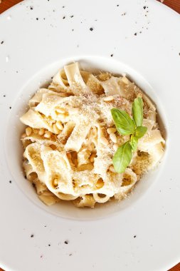 İtalyan makarna beyaz tabakta, sos ve parmesan peyniri ile