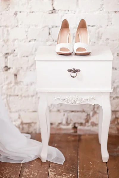 Hermosos zapatos de boda blancos en la mesita de noche vintage blanca —  Fotos de Stock