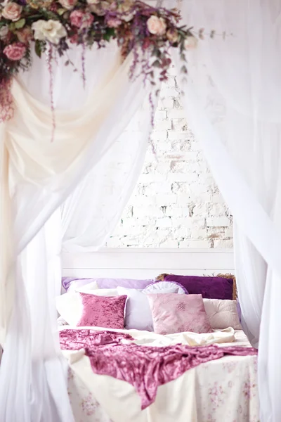 Λευκό άνετο κρεβάτι με μαξιλάρι εκλεκτής ποιότητας και λουλούδια — Φωτογραφία Αρχείου