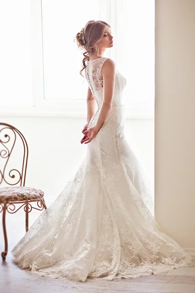 Joven novia atractiva en marfil ternura vestido de novia posando en vinatge interior —  Fotos de Stock