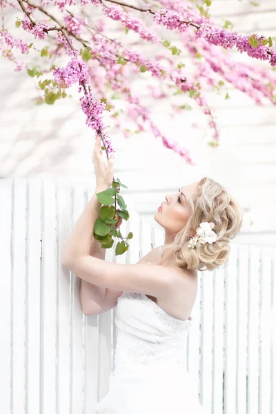 Atractiva joven novia posando cerca de rosas jardín — Foto de Stock