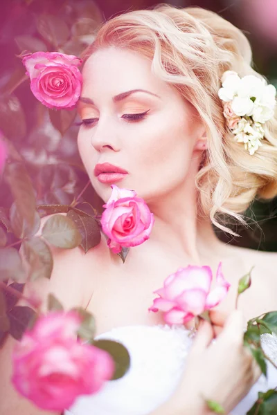 Atraktivní mladá nevěsta pózuje v blízkosti roses garden — Stock fotografie