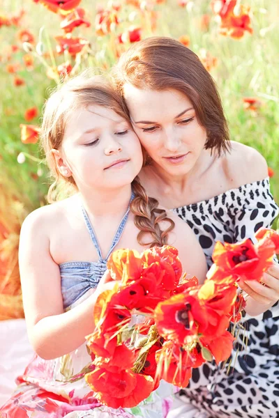 Moeder en dauhter maakt een krans van papaver bloemen op de picknick — Stockfoto