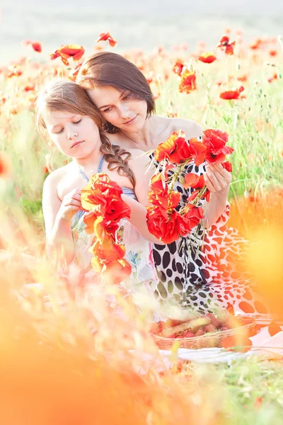 Moeder en dauhter maakt een krans van papaver bloemen op de picknick — Stockfoto