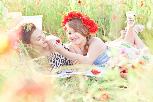 Mor och dotter som ligger på den vita filten och äta strawbe — Stockfoto