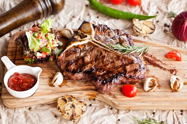 Bife Club Beef com molho de pimenta e legumes grelhados na tábua de corte em fundo de madeira escura Fotos De Bancos De Imagens