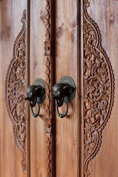 Старая деревянная дверь с бронзовой ручкой слона. Резьба по дереву — стоковое фото