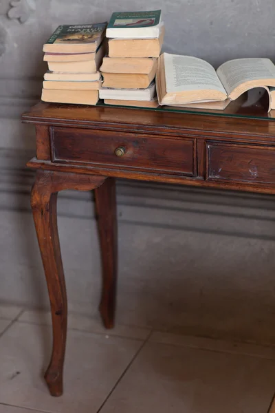 Stack of Magazine Books on Wooden Old Vintage Table near Grey Wa