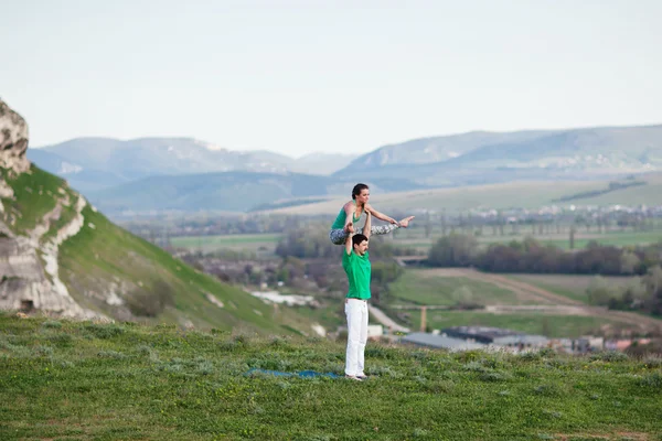 Acroyoga - równoważenie na nogi. Para praktykujących acroyoga w góry na wschód. — Zdjęcie stockowe