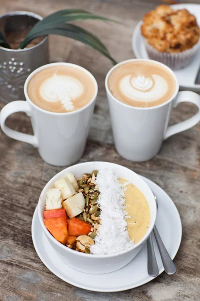 İki bardak sıcak Latte sanat kahve ile kek ve meyve çiğ muesl — Stok fotoğraf