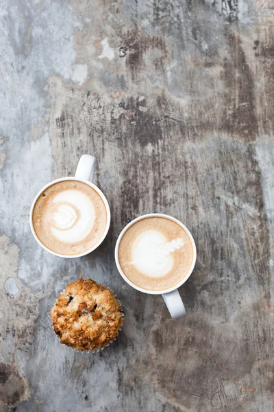 Uma xícara de café quente Latte Art com muffin na mesa cinza vintage — Fotografia de Stock