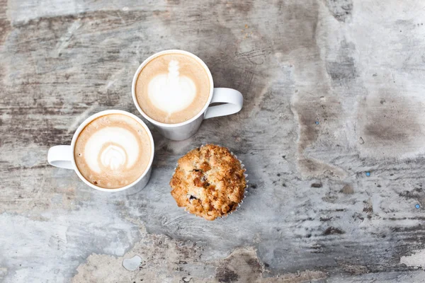 Uma xícara de café quente Latte Art com muffin na mesa cinza vintage — Fotografia de Stock