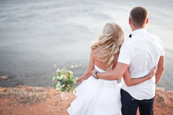 Élégante mariée magnifique et marié marchant au coucher du soleil sur le backgr — Photo