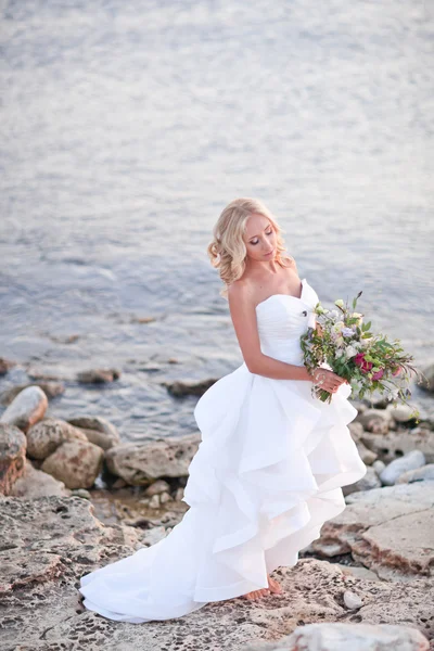 Retrato de noiva ao longo da costa do mar segurando belo buquê de casamento — Fotografia de Stock