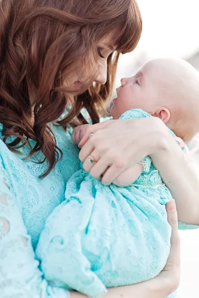 Porträtt av glad kärleksfull mor i blå klänning och hennes baby utomhu — Stockfoto