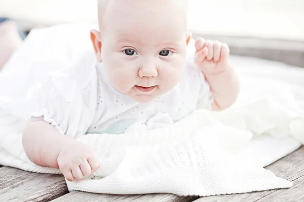 Bambino bambino sdraiato felice sorridente sulla coperta di maglia su un bianco — Foto Stock