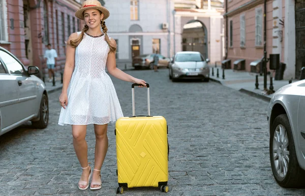 Жінка мандрівник туристи прогулюється по міських вулицях з великою жовтою валізою . — стокове фото