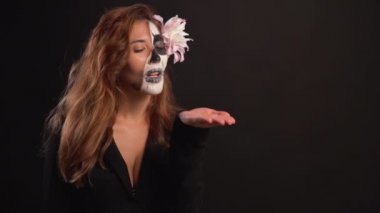 Karanlık bir arka planda Cadılar Bayramı için makyajlı genç bir kadının portresi. Parıltıyı yok ediyor. Metni kopyala