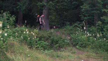 Sırt çantalı bir turist ormandan çıkar ve tepeden aşağı iner.