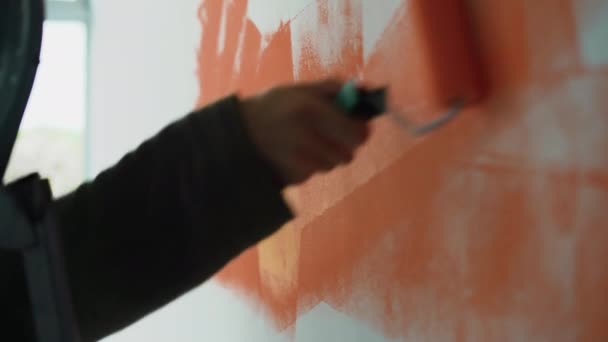 Close-up van een mensenhand. Schilder de muur met oranje verf met een roller. — Stockvideo