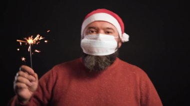 Siyah arka planda Noel Baba şapkalı sakallı adam. Yüzüne bir tıbbi maske takılır. Bengil ateşi yanıyor.