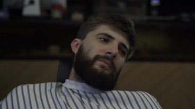 Sakallı bir adamın yakın plan yüzü, sakalını tarayan berber..