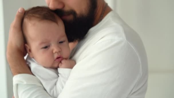 Közelkép egy újszülött gyerekről, akit az apja a karjaiban tart és csókol. — Stock videók