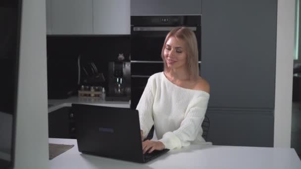 Kobieta bizneswoman pracuje na laptopie siedząc w domu w kuchni — Wideo stockowe