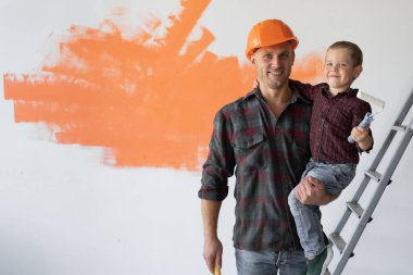 Mutlu genç aile evlerini yeniliyor, baba oğlunu kollarında tutuyor..