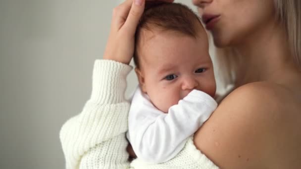 Közelkép egy újszülött arcáról, anya a karjaiban tartja és simogatja a fejét. — Stock videók
