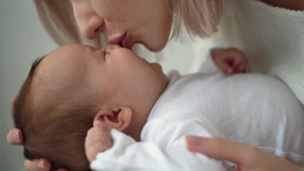 Közelkép egy újszülött babáról, női kézsimogatás. anya csók az orrán — Stock videók