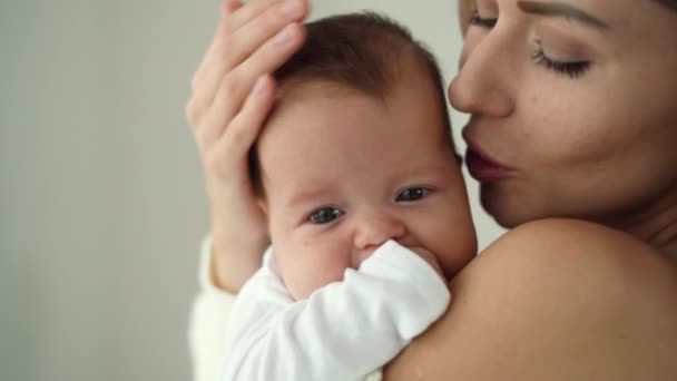 Közelkép egy újszülött arcáról, anya megfogja és arcon csókolja. — Stock videók
