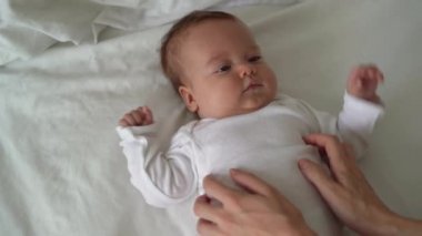 Yatakta yatan yeni doğmuş bir bebeğin portresi. Kadın eli sıvazlıyor. Mutlu aile kavramı