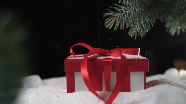 Hermosa caja con un primer plano de lazo. La nieve fina cae en el regalo. Copiar espacio — Vídeo de stock