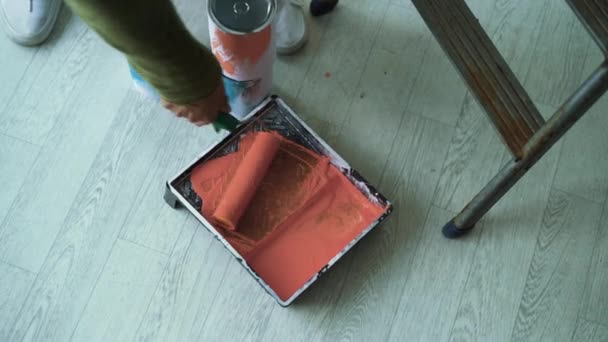 Vista superior, o rolo é mergulhado em uma bandeja de tinta laranja. conceito de renovação de casa — Vídeo de Stock