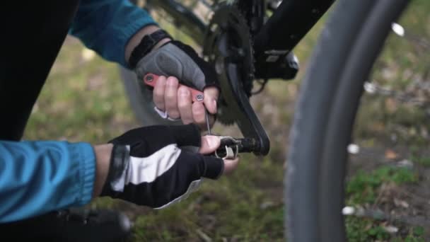 Κοντινό πλάνο των αρσενικών χεριών ρυθμίστε τα πεντάλ σε ένα ποδήλατο. — Αρχείο Βίντεο