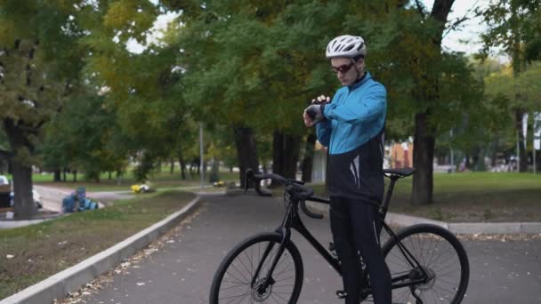 Sportsman biker med GPS-aktivitetsmätare fitness klocka vid träning i parken Sport man med hjälp av sin klocka fitness tracker app. — Stockvideo