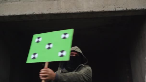 Мужчина в черной маске держит плакат в руках и машет им в разных направлениях. Скопируйте точки слежения. Чистый зелёный экран. — стоковое видео