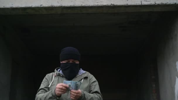 Un uomo con una maschera nera conta i soldi e se li mette in tasca. Solleva un poster. Copia i punti di tracciamento spaziale. Schermo bianco verde. — Video Stock