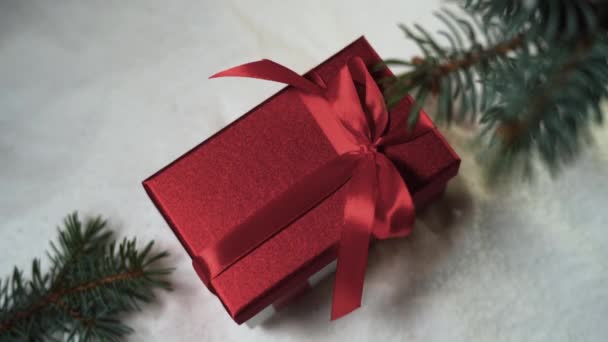 Horní pohled na červenou krabici leží na sněhu pod vánočním stromečkem. Ženská ruka ji vezme — Stock video