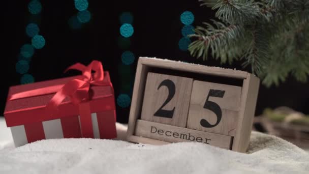 Un calendrier perpétuel en bois se trouve sur la neige, sur elle la date est le 25 Décembre. — Video