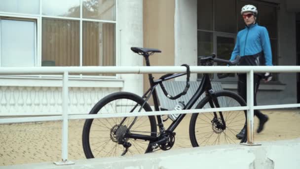 Un hombre se acerca a la bicicleta, abre la cerradura de combinación y quita la cadena — Vídeo de stock