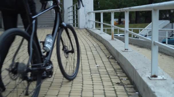Bisikletli bir adam tırabzana yaklaşır, araçtan iner ve zinciri takar. Güvenlik kavramı — Stok video