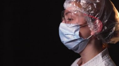 Yan bakış açısı yorgun kadın doktor yüzünden koruyucu bir maske çıkarıyor ve derin derin nefes alıyor. COVID-19 salgını sırasında çok çalışan doktorlar kavramı