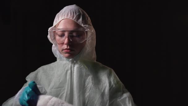 Young woman dressed in a white protective suit puts a red santa claus hat on her head. Concept of christmas and new year in hospital during covid-19 — Stock Video