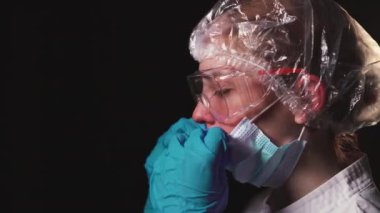 Yan görüş, yorgun kadın doktor yüzüne koruyucu bir maske takıyor. COVID-19 salgını sırasında çok çalışan doktorlar kavramı